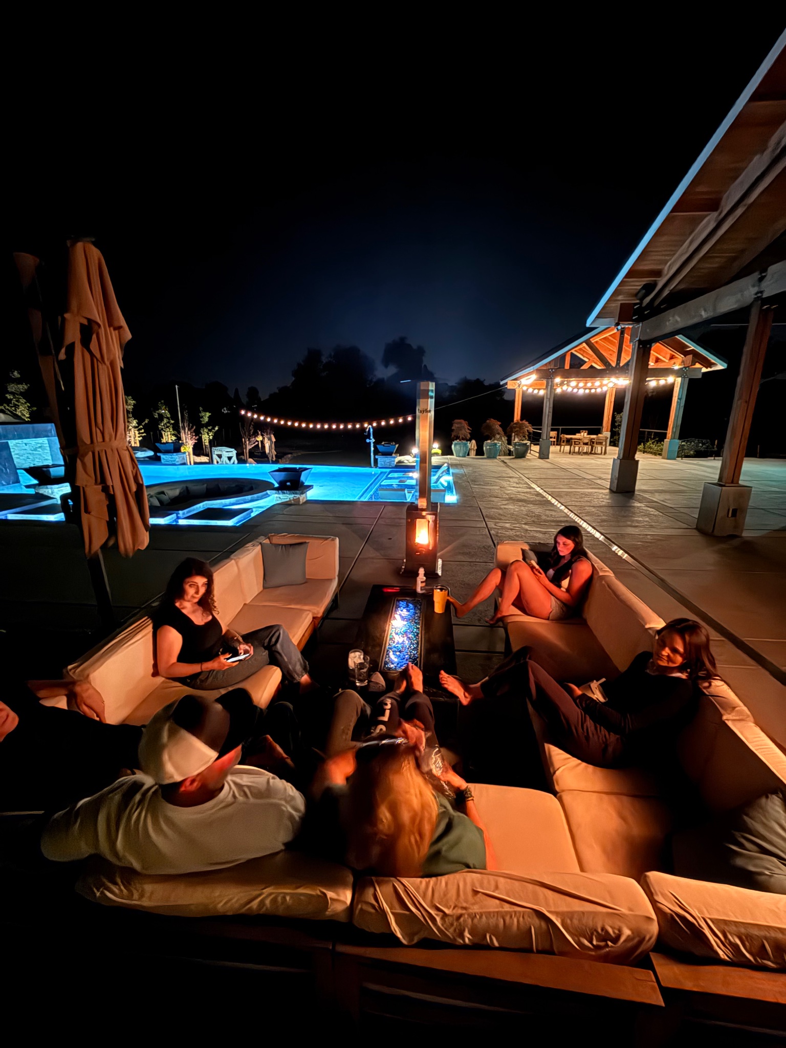 Friends gathered around Sierra Stoves heater poolside at night